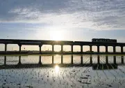 水鏡に映る夕日と列車、大洗鹿島線沿線で田植えの季節